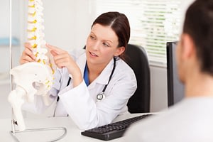 A female doctor is pointing on a bone in a spine